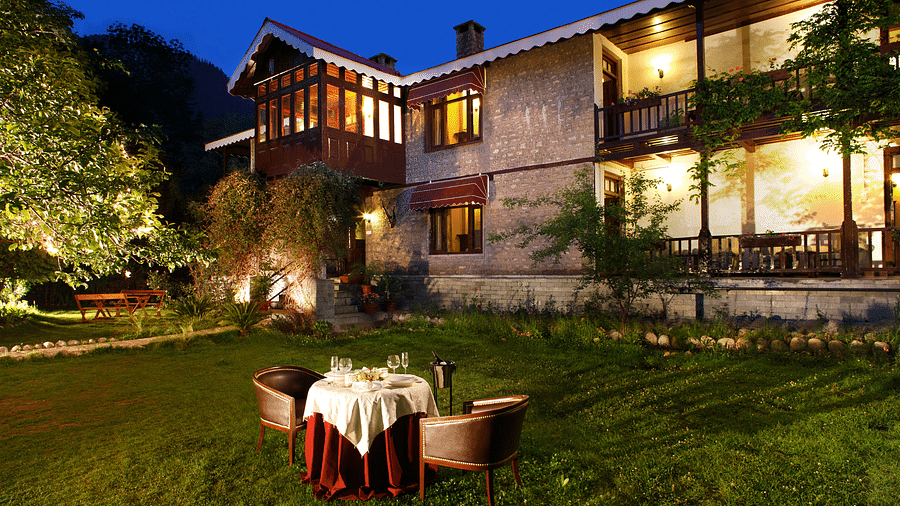 a facade of Bedzzz Xclusiv Baikunth, Manali with outdoor seating during evening