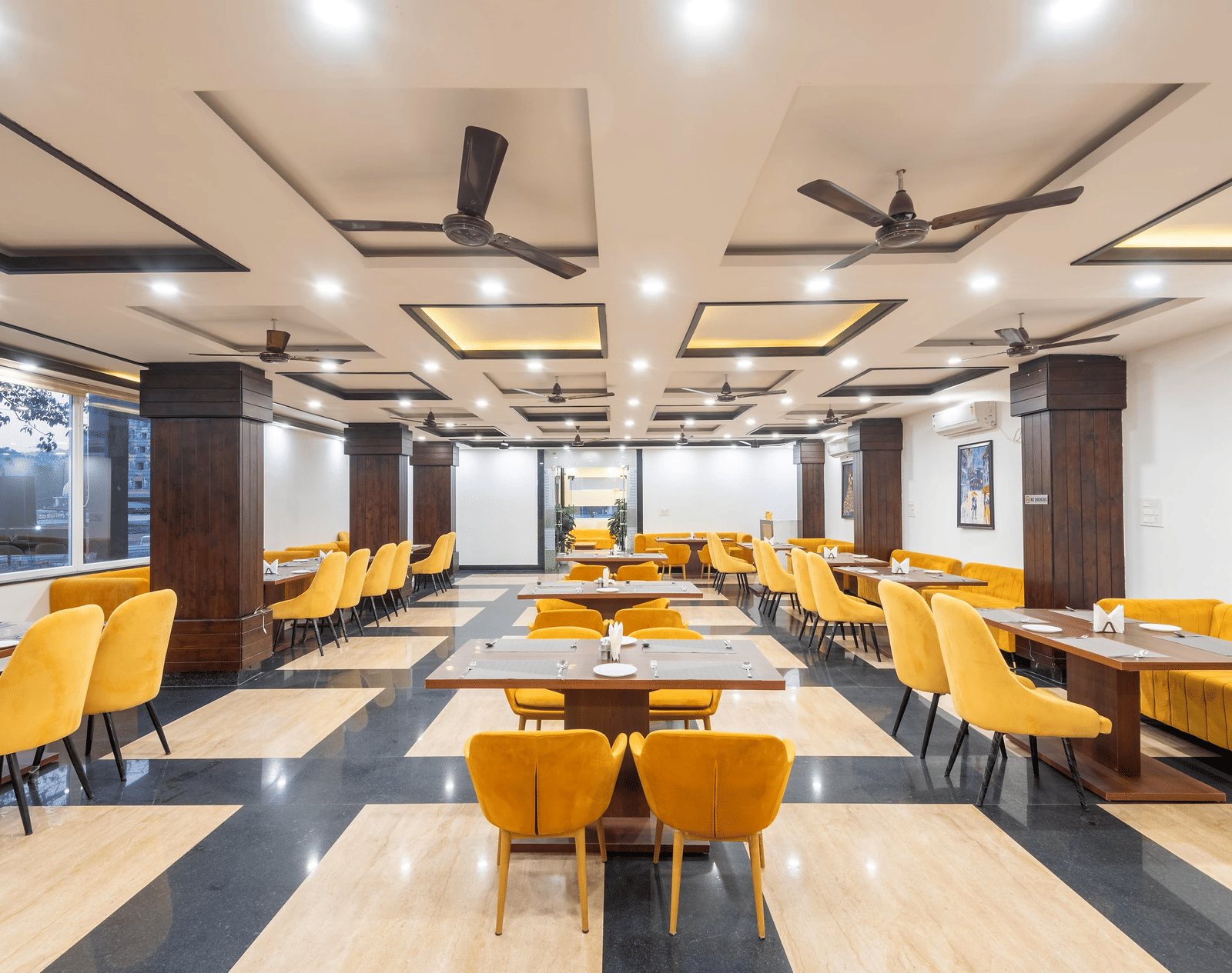A dining area with several tables, chairs, and ceiling fans at Perfectstayz Premium Shanti Heritage, Haridwar