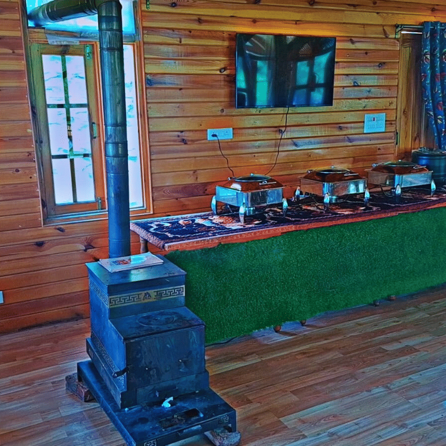 An indoor buffet counter at Dawat e Drung by FrozenFall Resort, Drung, Tangmarg, with dishes arranged on a long table in a wood-panelled room.