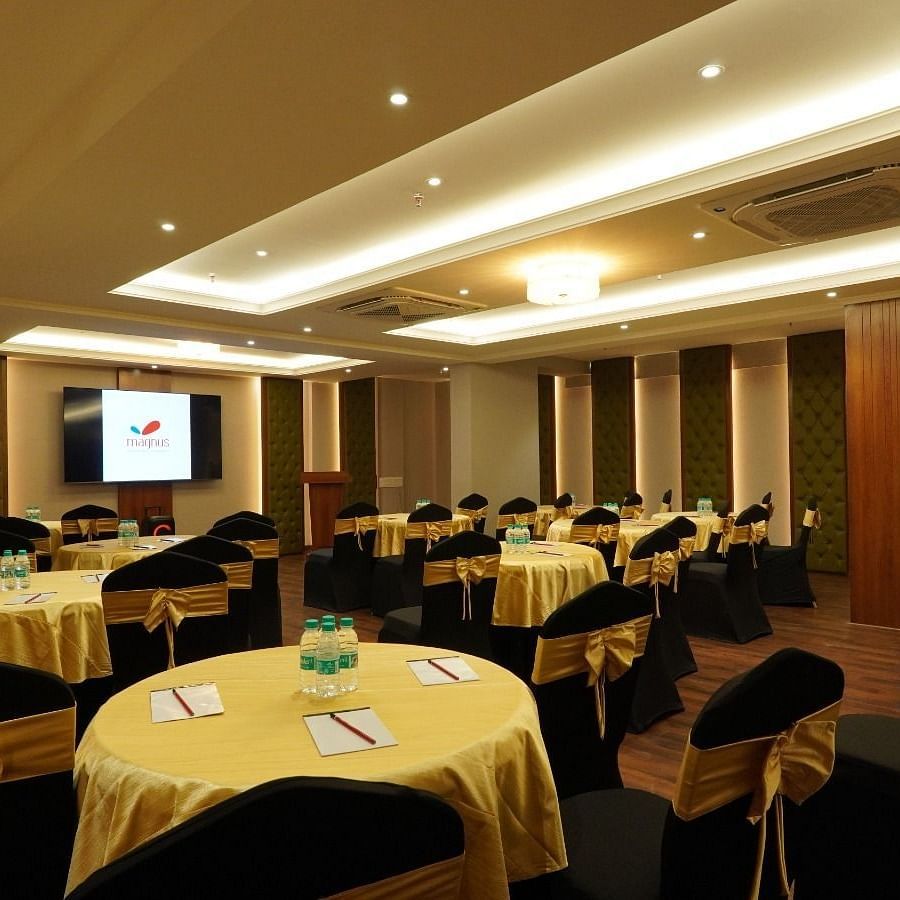 Modern boardroom featuring a long polished wooden table, high-back black chairs, soft ambient lighting, and wood-panelled walls – Magnus Nexstar Suites, Kalyani Nagar