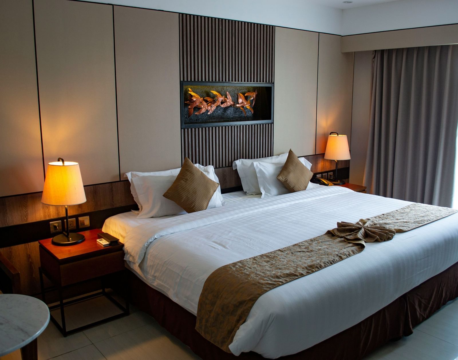 a double bed in a hotel room with bedside tables with lamps on either side of it