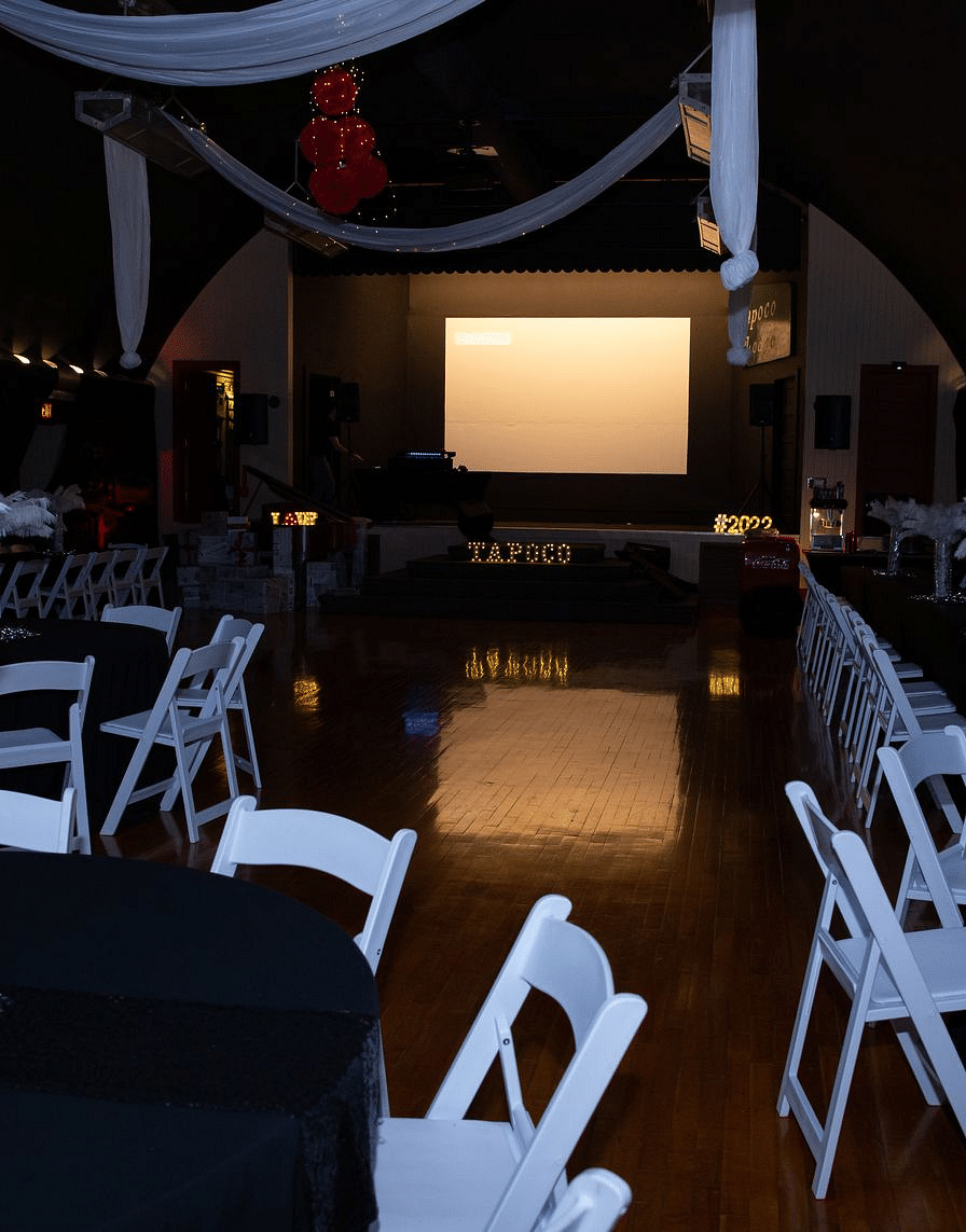 a projector screen at the Tin Can Theater with several tables and chairs arranged in front of it - Historic Tapoco Lodge