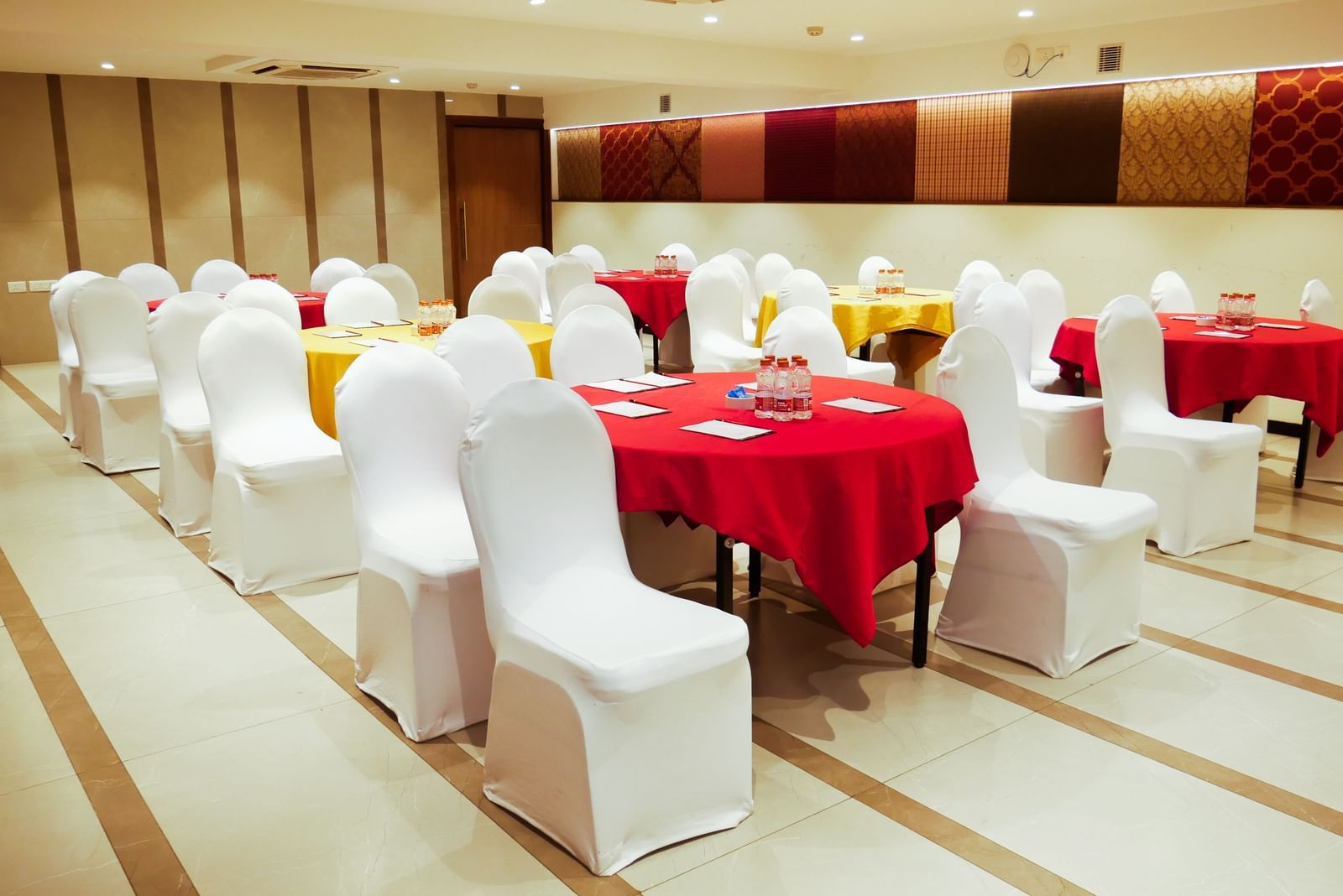 A well decorated banquet hall set up with round tables draped in red, ready for an event at Shilton Dee Cee.