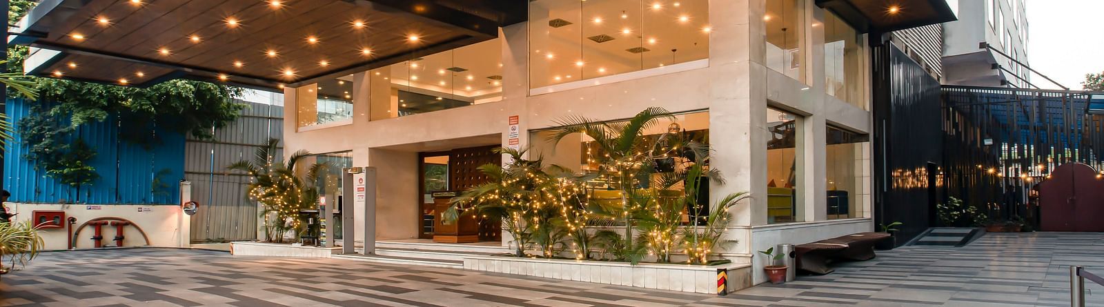 Facade of The Cunningham Hotel featuring its entrance with a stylish black canopy, warm lighting and glass walls
