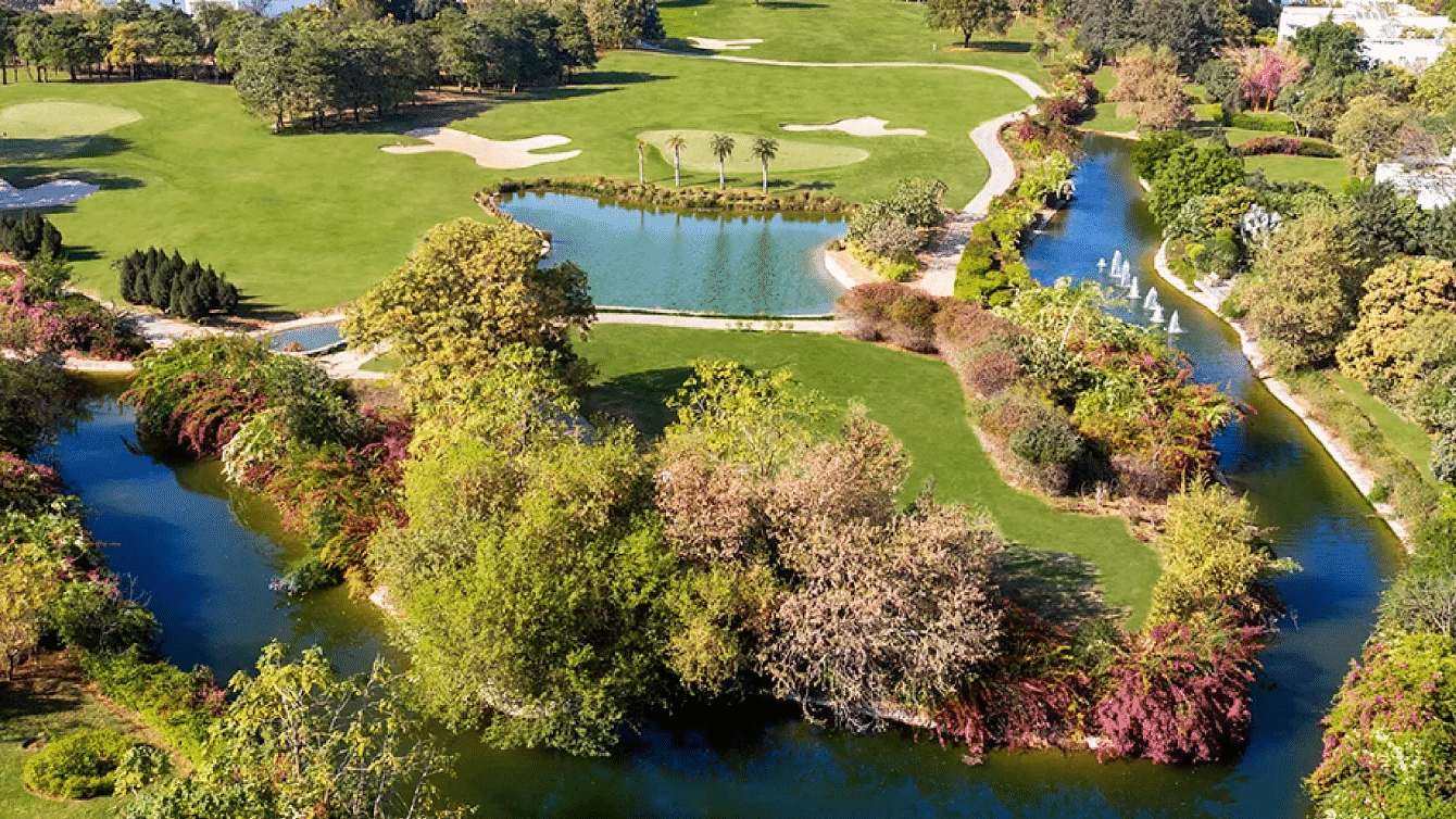 Aerial view of green landscape with buildings and golf course near Karma Chalets.