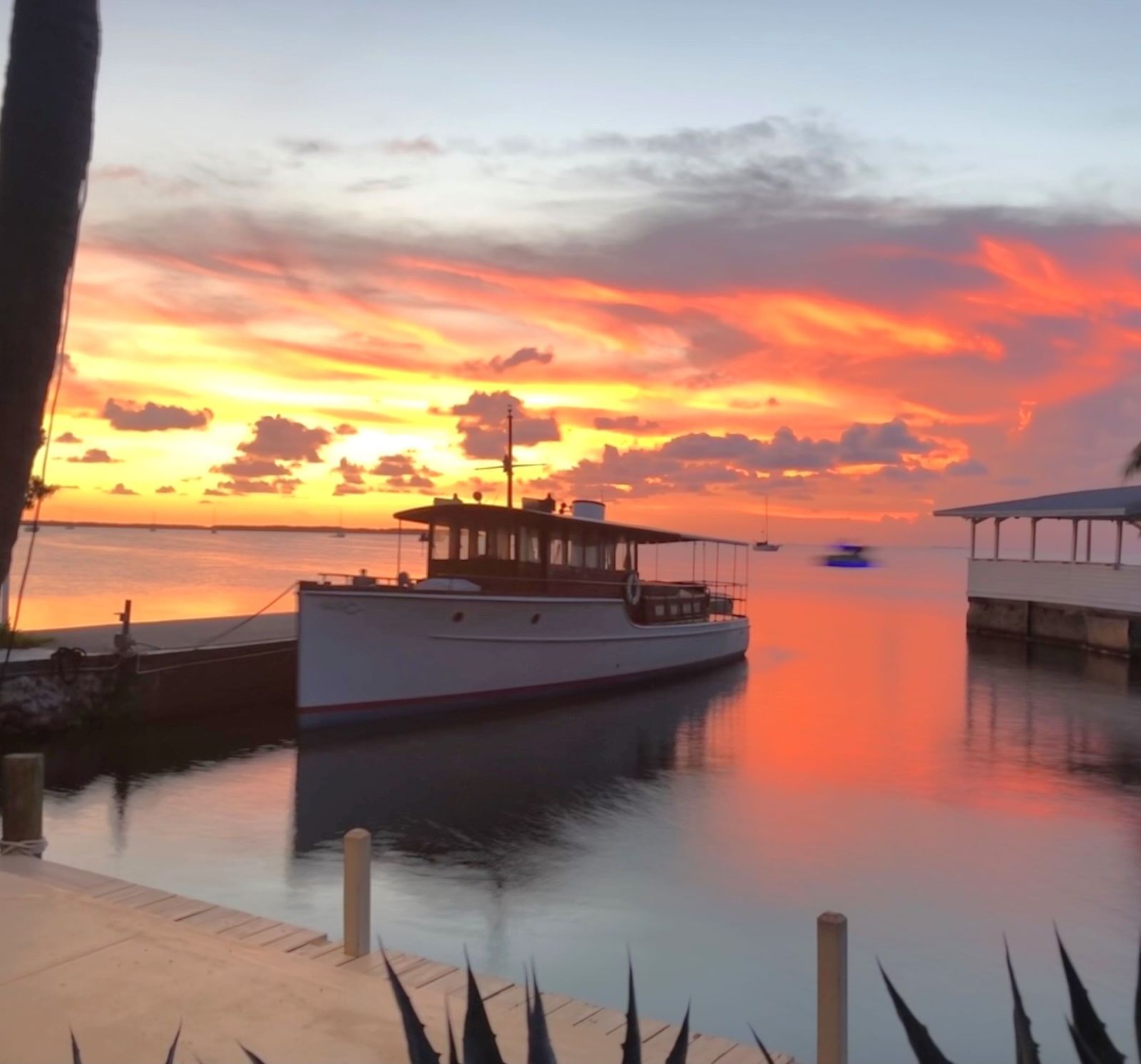 A beautiful sunset featuring a small vessel standing still besides a wooden dock at Casa Morada.