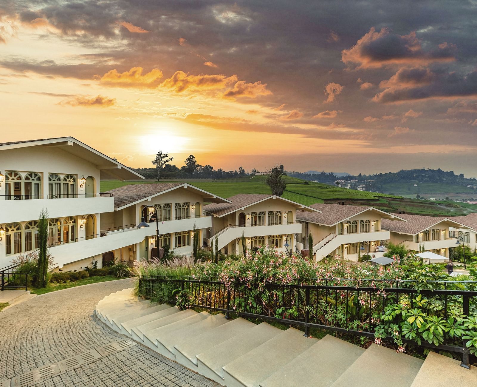 Walkway weaving through Mango Hill Shola, Ooty, flanked by resort buildings and landscaped surroundings.