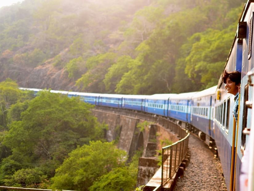 A train chugs through a vast desert landscape.
