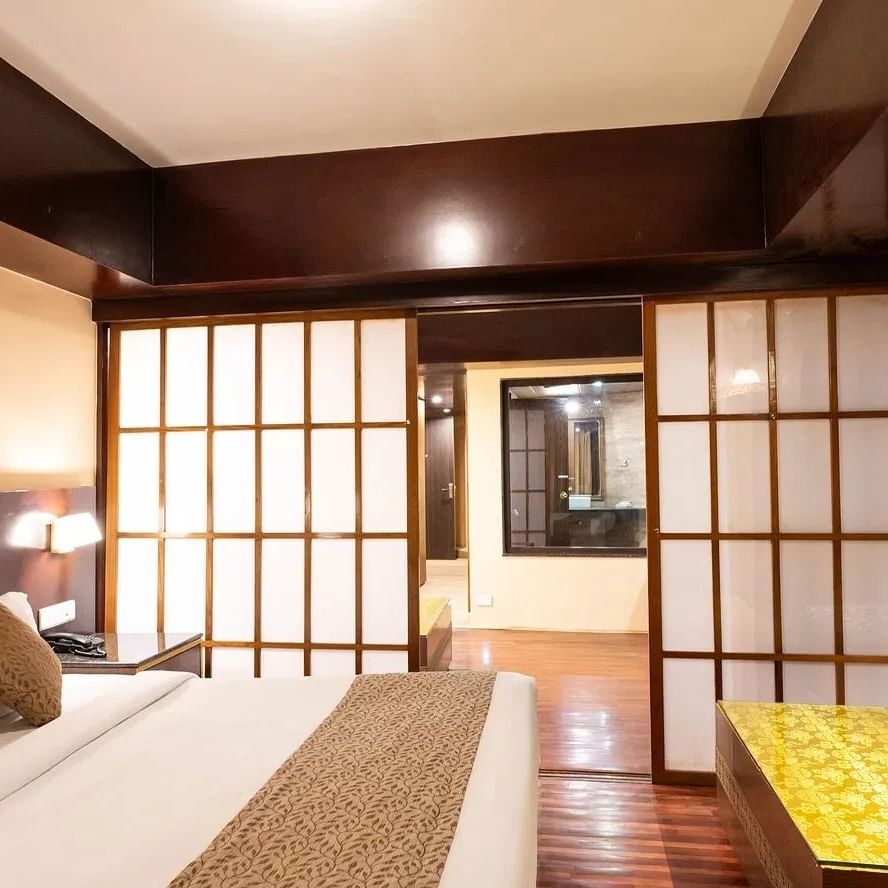 Suite at Avianna Hungry Jack, Gangtok featuring a plush bed, wooden flooring, shoji-style sliding doors, and elegant seating area with patterned cushions.