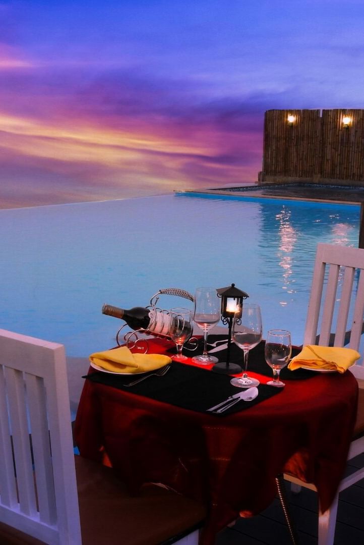 Outdoor dining setup beside an infinity pool during sunset at Polo Resort Cherrapunjee.