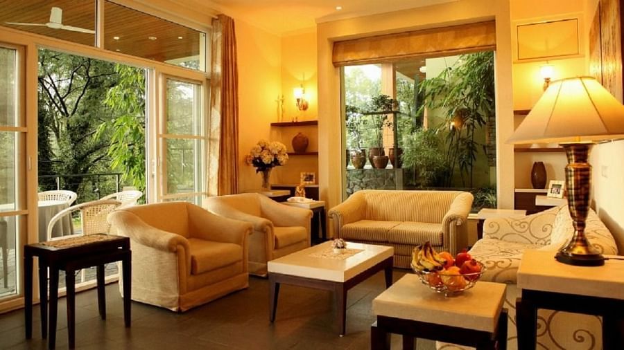 side angle view of a spacious living room with modern interior decor and large windows facing the tea gardensLiving RoomLiving Room3 - Lamrin Norwood Green Palampur