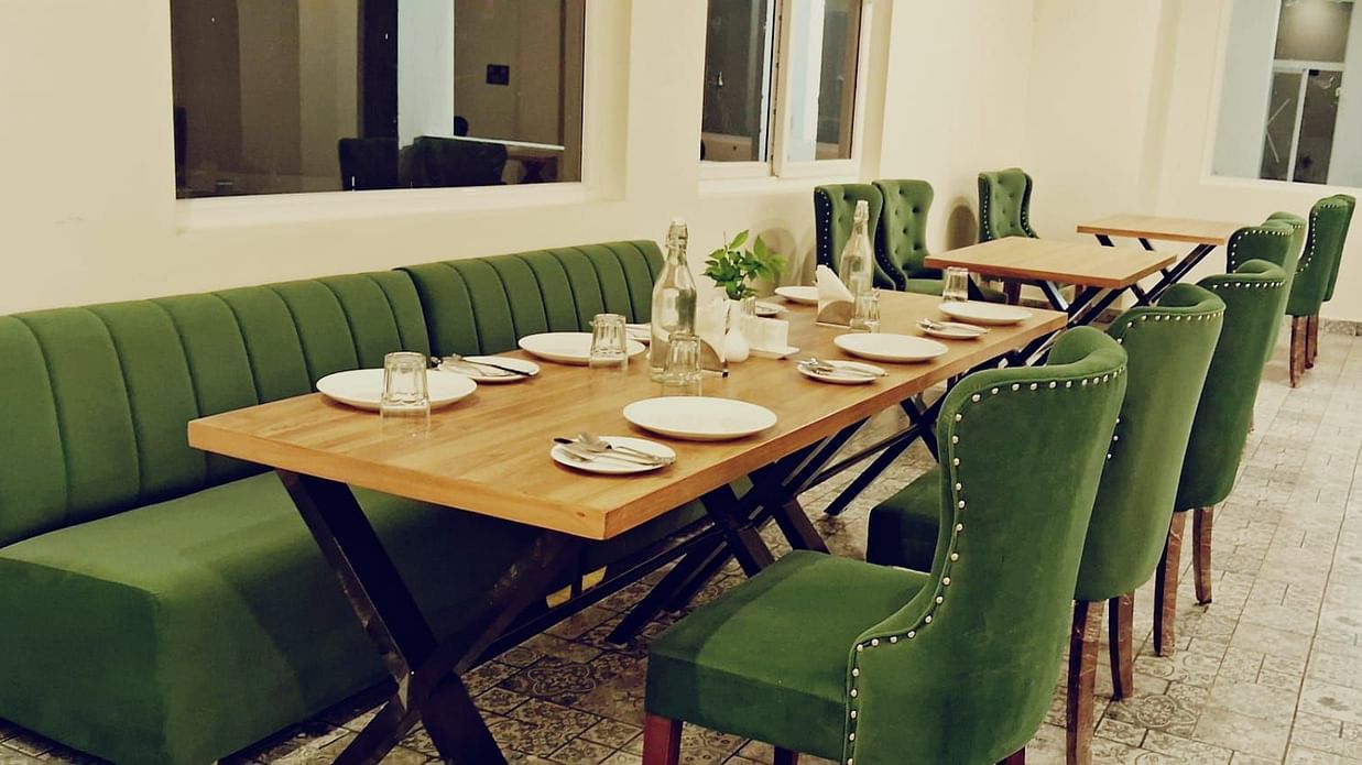 Restaurant with sofa and chairs with cutlery on the table at A’otel by Clarks Inn Palampur
