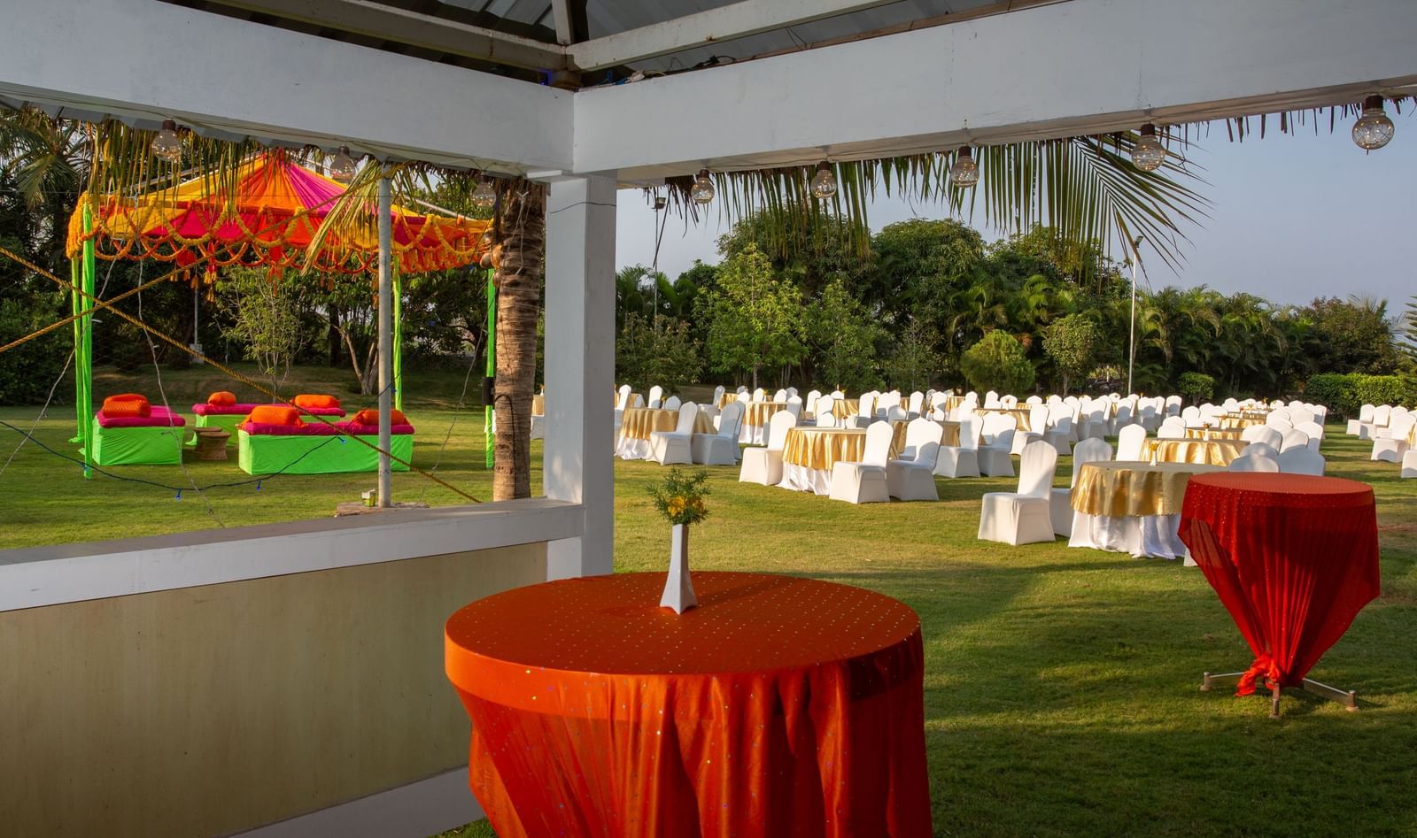 An outdoor event setup with an orange and yellow tent over a table, surrounded by white chairs | Citrus Garden | Grand Bay Resort and Spa