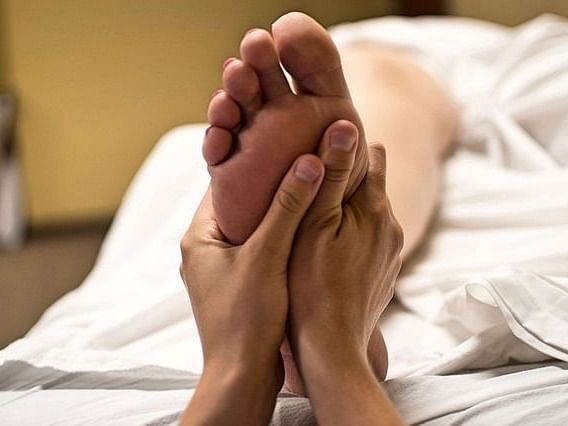 Close-up of feet receiving a relaxing massage on a bed.
