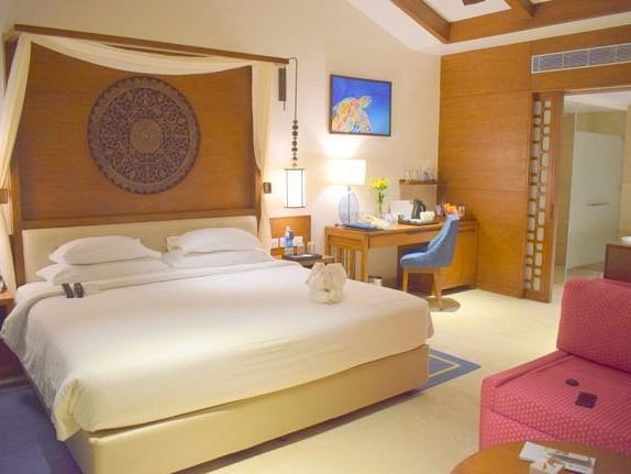 An image of  a bedroom with a working desk and a chair.