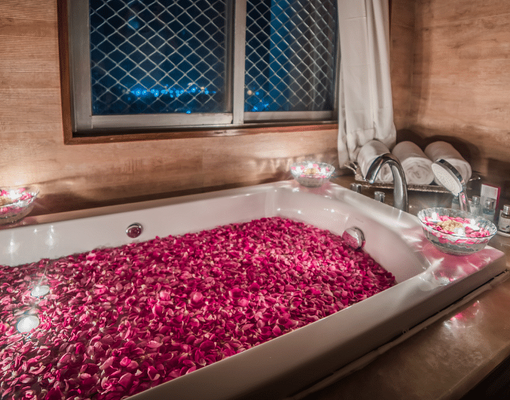 A filled bath tub at Sitara Luxury Hotel in Hyderabad near Ramoji Film City with rose petals and candles around it