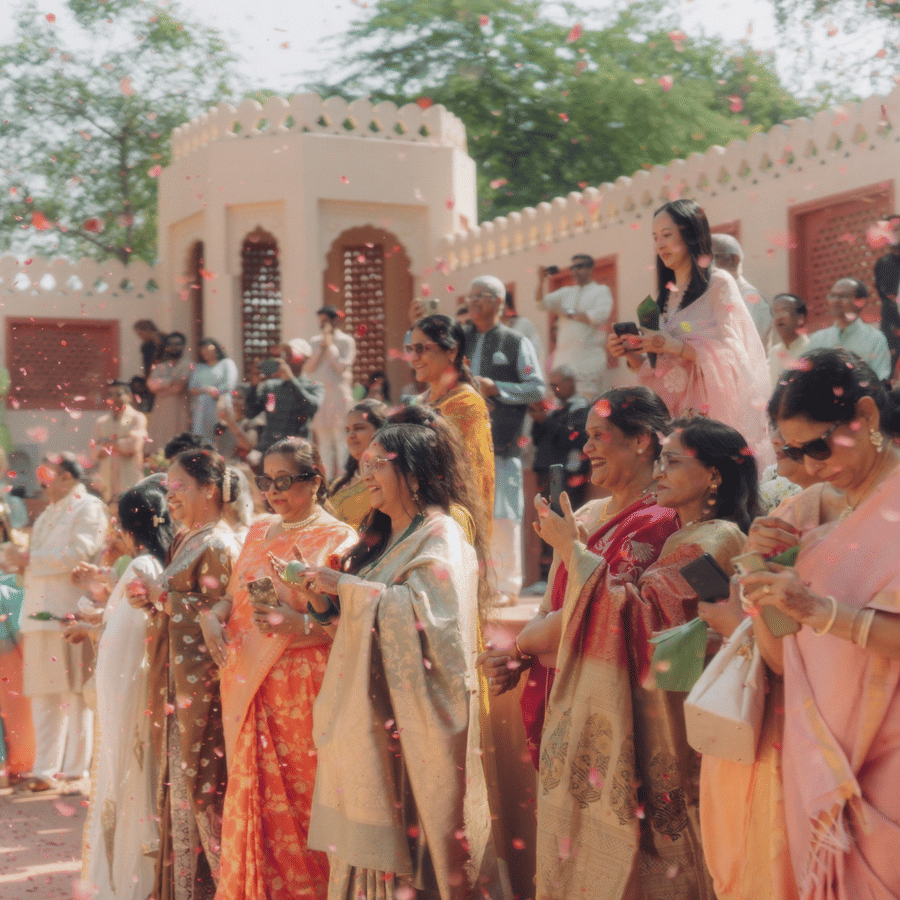 Guests lined up along red stone courtyard steps clapping and celebrating at Umaid Palace.