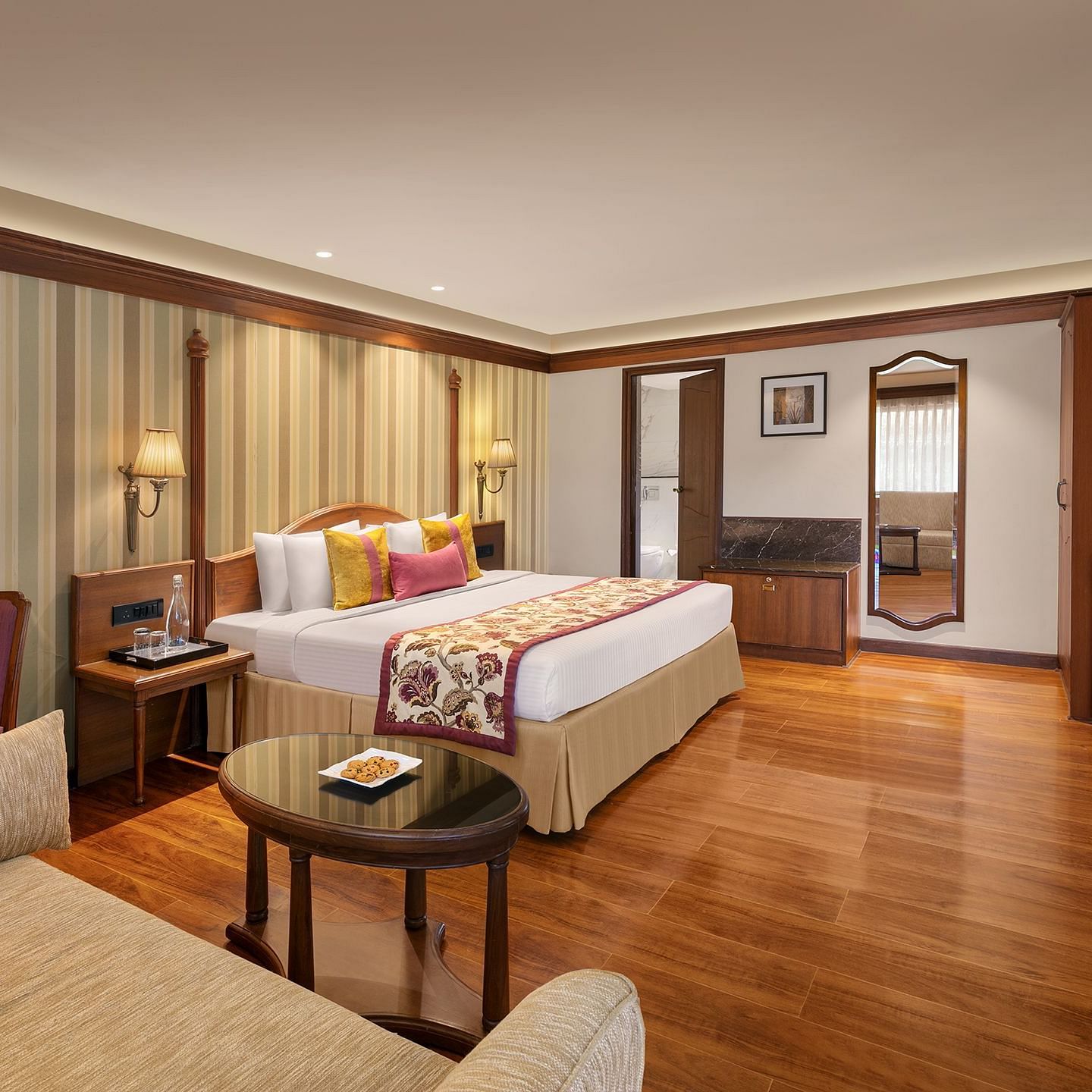 The image shows a luxurious hotel room with a comfortable bed, elegant furniture 