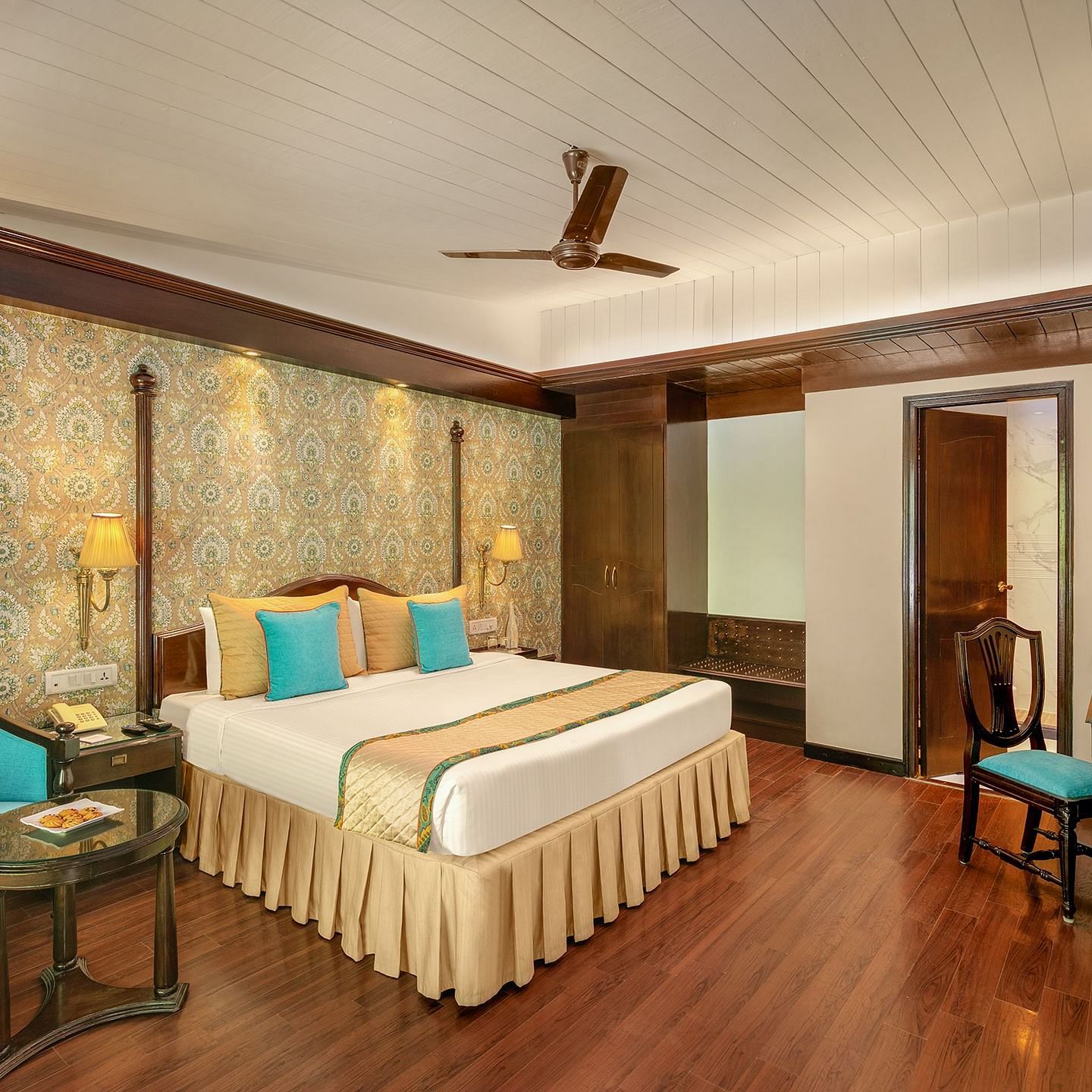 A cozy bedroom with a comfortable bed, warm lighting, and a view of the forest through a large window at Shervani Hilltop Nainital 