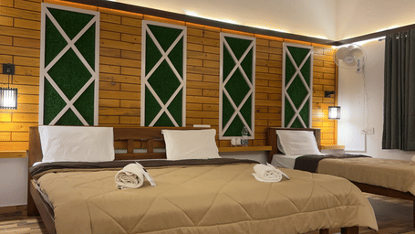 A Family Room With Garden View 2, of Hatti Eden Coorg aturing a large bed with neutral-toned linens and multiple white pillows. The headboard wall is a focal point, decorated with three vertical, rectangular panels of dark textured material accented by lig