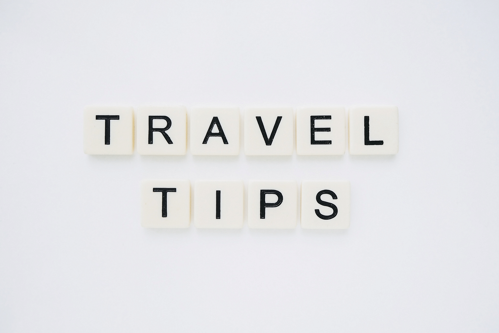 An overview of scrabble tiles making the word Travel tips on top of a white background.