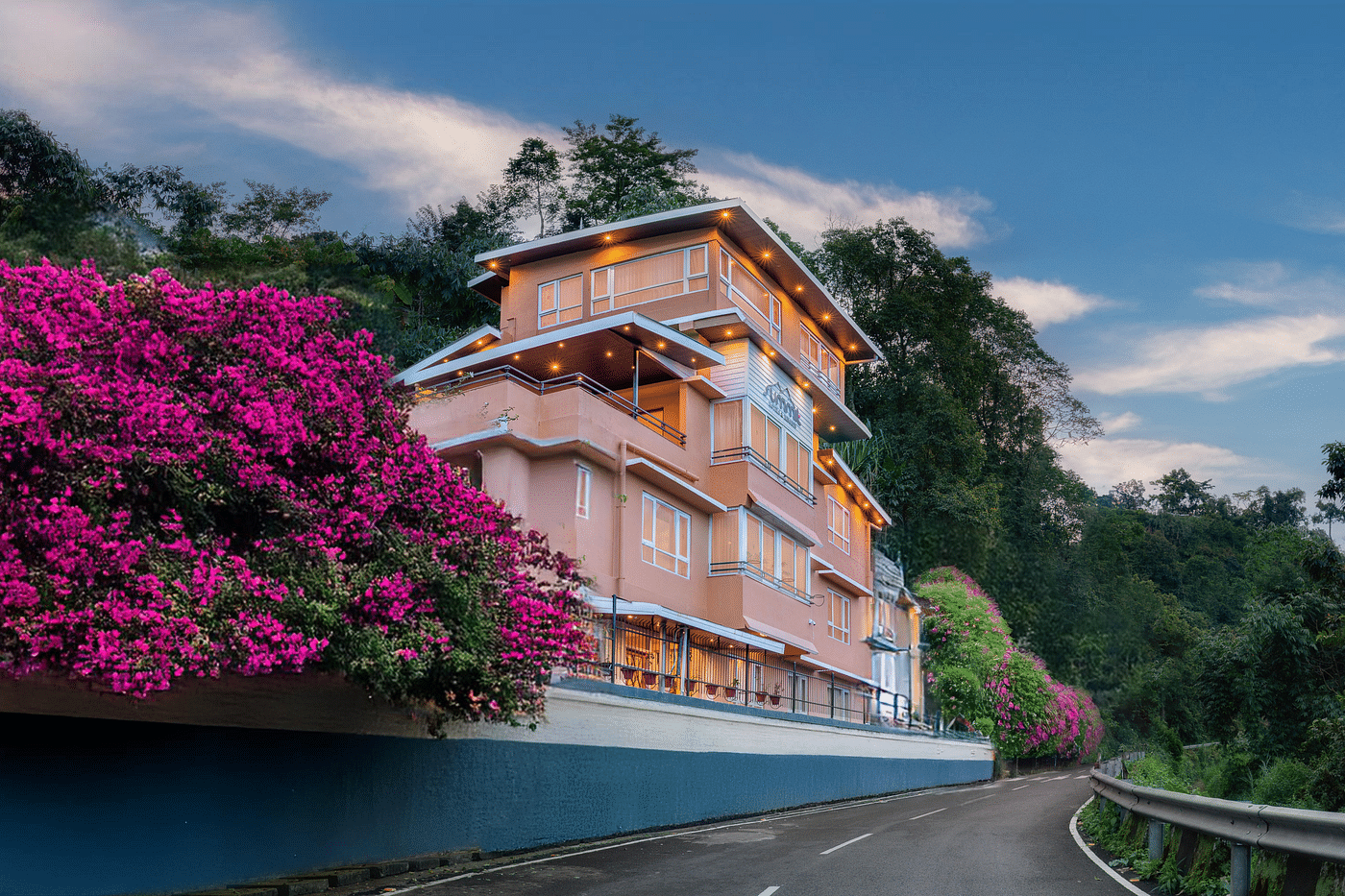 Facade of Summit Bougainvillea Tea Resort in Kurseong, framed by vibrant Bougainvillea plants, with a stunning sunset sky in the background