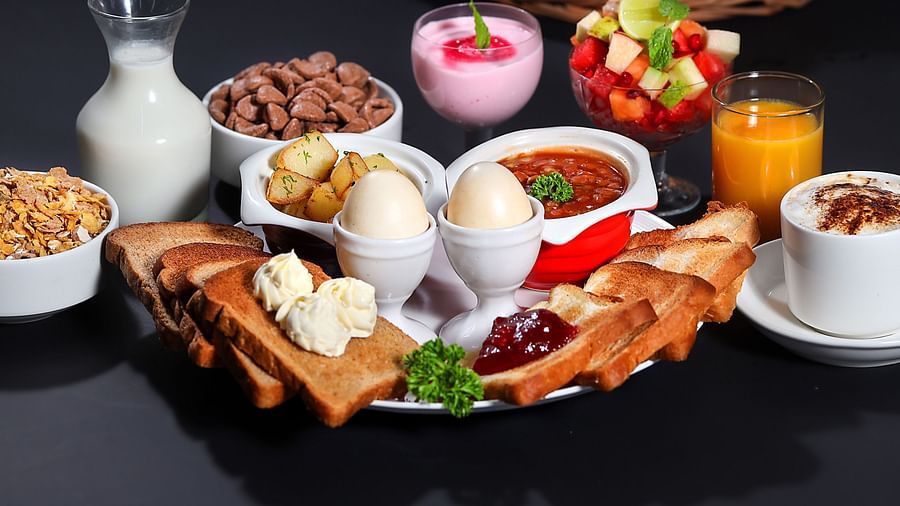 image of a vast platter of breakfast items well kept on a plate featuring 2 eggs in egg stand along with toasts and various other things