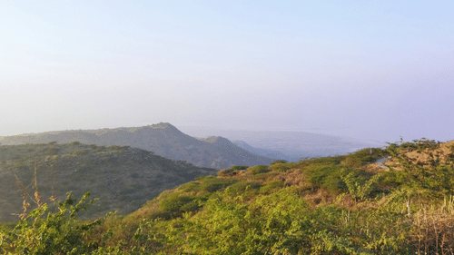 A landscape view of rolling hills and a valley in the distance under a clear sky.