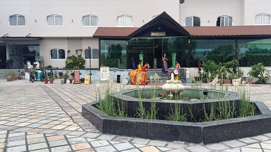 A building with a covered entrance and a decorative fountain in a paved courtyard.- Bamboo Saa Resort & Spa, Udaipur