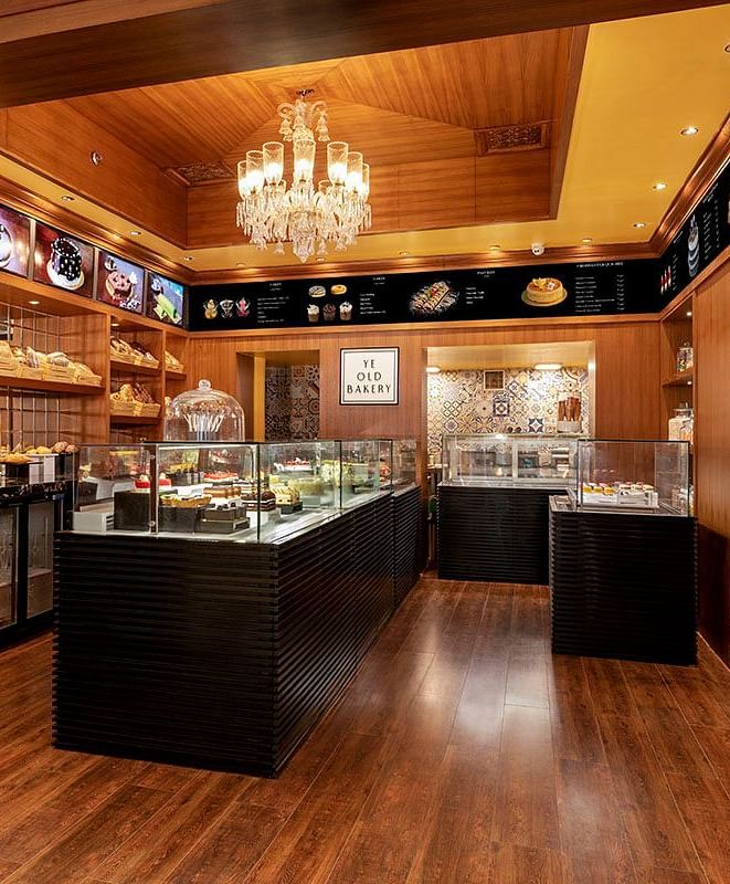 Ye Old Bakery at The Claridges New Delhi, showcasing an elegant chandelier and a curated selection of baked delights in a stylish glass display
