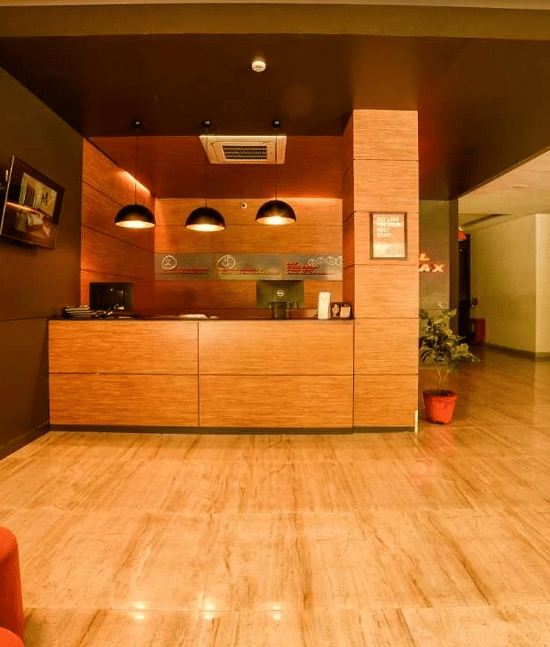 A lobby area of Max Hotel Jabalpur, featuring a wooden reception desk, a polished floor, and seating areas.