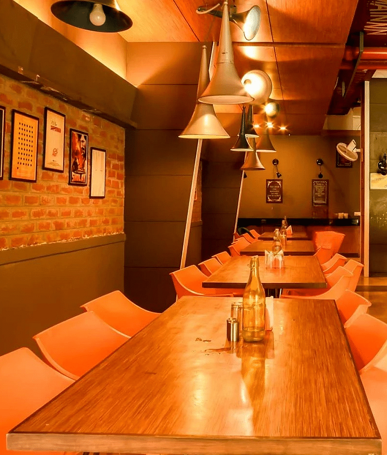 The interior of Mumbai Masala Restaurant, featuring chairs and wooden tables at Max Hotel Prayagraj.