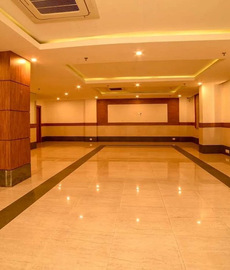 An interior of a banquet hall with tile flooring and warm lighting at Max Hotel Prayagraj.