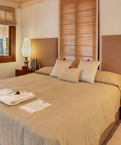 A bedroom with a bed, lamps, and a view of a garden - Shreyas Retreat