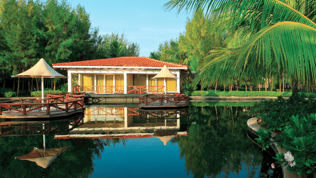 Exterior of the Bermuda villa with a deck in front of a lake in a peaceful lush setting at OCEAN SPRAY, Pondicherry