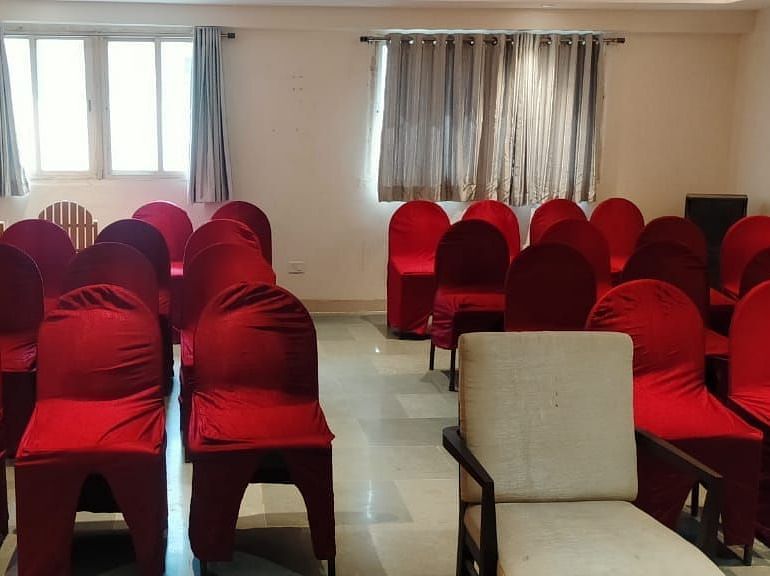 Spacious seminar hall at Lords Eco Inn Dahej featuring red fabric chairs arranged in rows with natural lighting from large windows