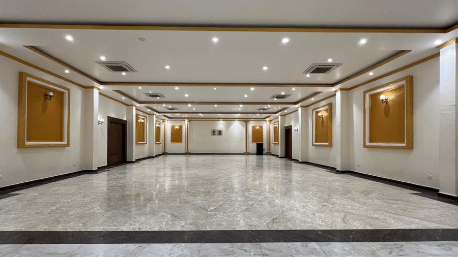 A long corridor with framed artworks and marble flooring at AS Hotels, Khajuraho.