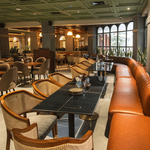 An image of a restaurant featuring a bunch of well-decorated tables, chairs, and sofas in daytime - Hotel Polo Towers, Shillong 