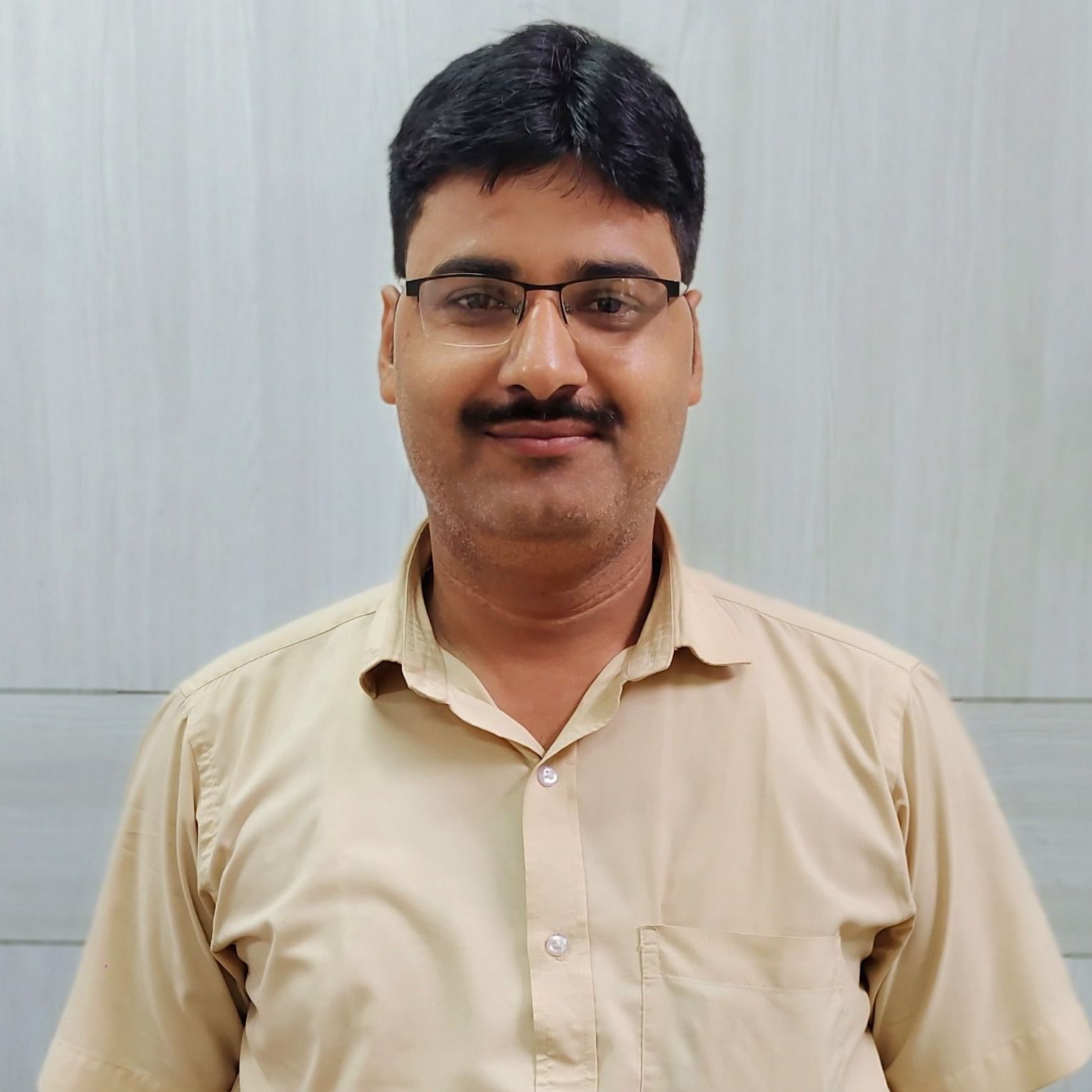 A man with glasses and a mustache smiles at the camera