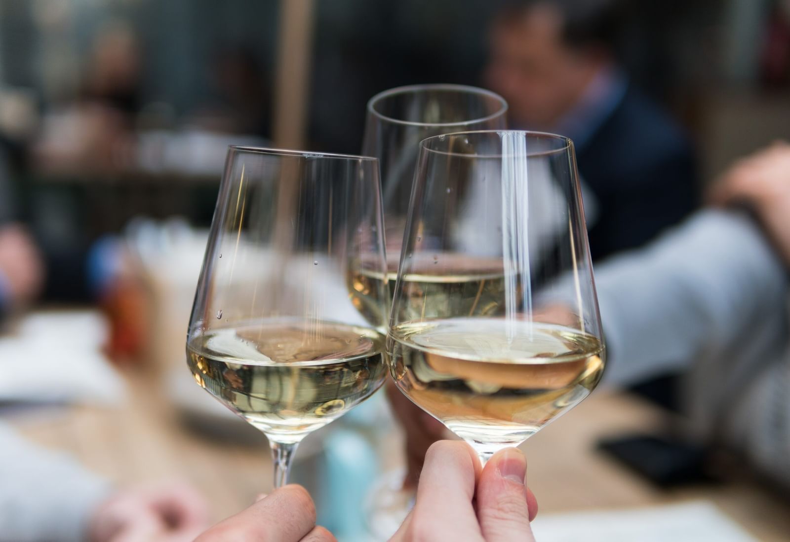 A close-up shot of 3 glasses of white wine clinking together for a toast.