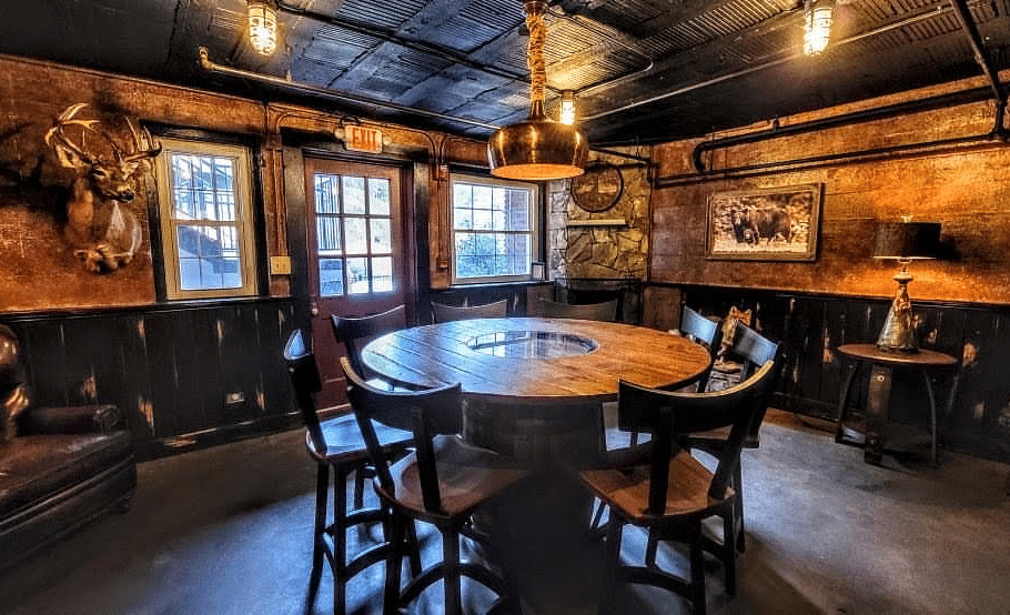 a circle shaped table surrounded by wooden chairs in a dimly lit room - Historic Tapoco Lodge