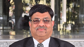 The second image is a portrait of Pushpendra Bansal, a middle-aged man with a mustache and glasses, wearing a black suit and a patterned tie.