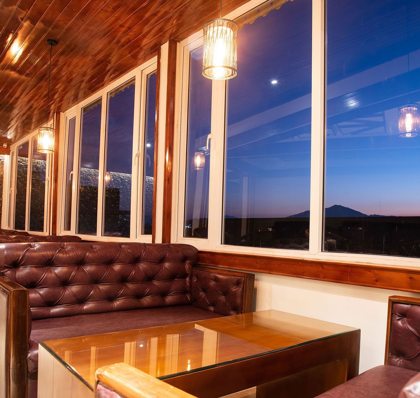 A seating arrangement of a bar in gangtok with leather couches and a well furnished table - Summit North Star, Gangtok