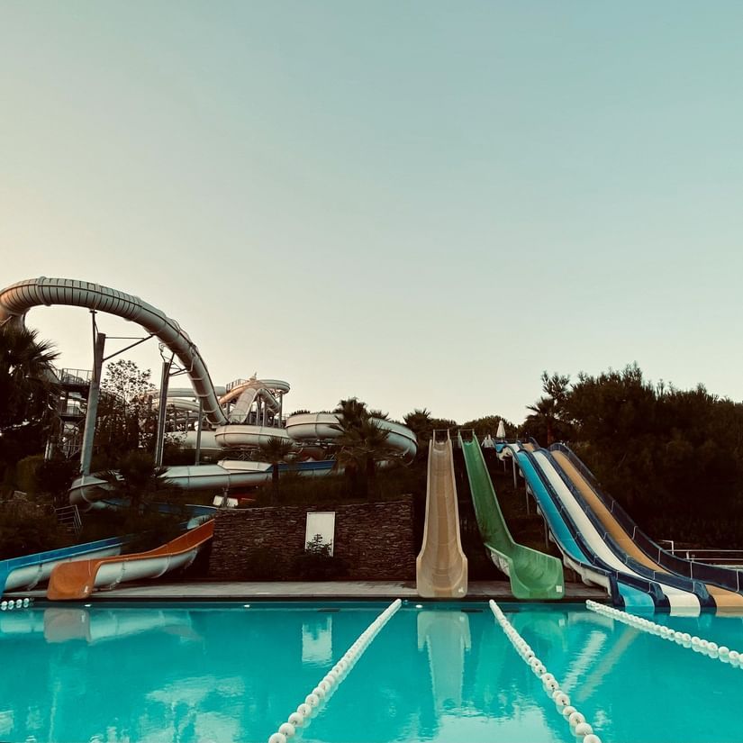 Colorful water slides leading into a large pool at a water park.