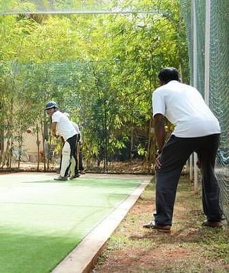 Two people playing a sport on a field, outdoor setting with trees in the background - Shreyas Retreat