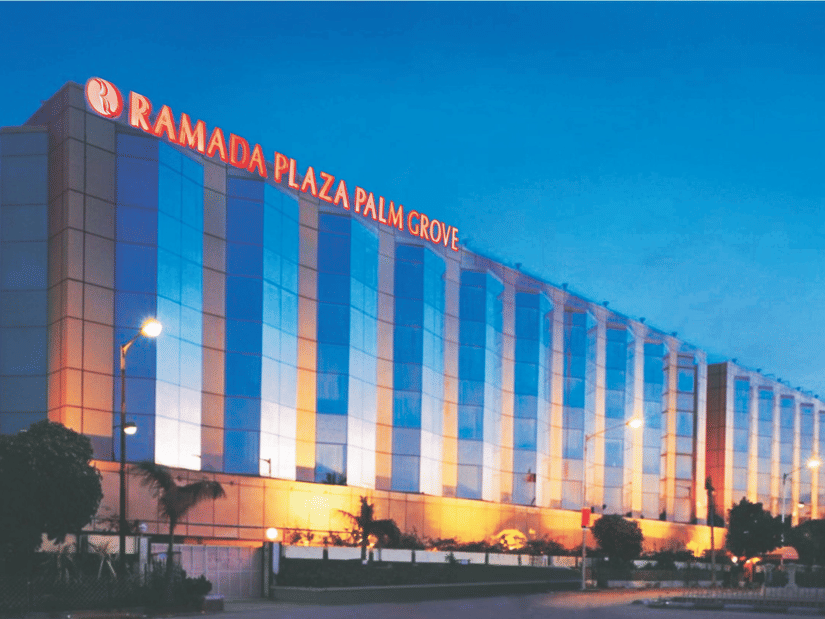 Facade of Hotel Ramada Plaza Palm Grove, Juhu, Mumbai, during twilight hour with the lights on.