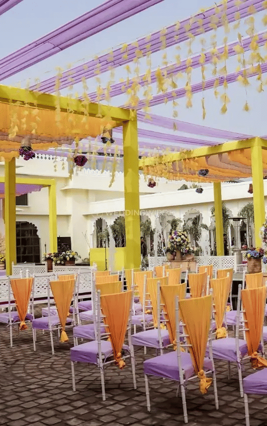 Rows of chairs arranged under a yellow and purple canopy structure set for an outdoor event at Beelwa Palace, Jaipur