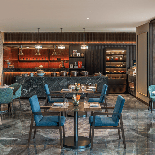 Executive Lounge with a bar counter, teal chairs and marble flooring at The Residency Signature Madurai.