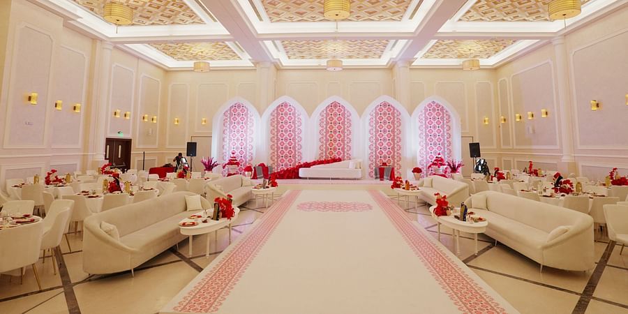 A wide view of a decorated banquet hall at La Maison, Doha, featuring a patterned ceiling and arched doorways.