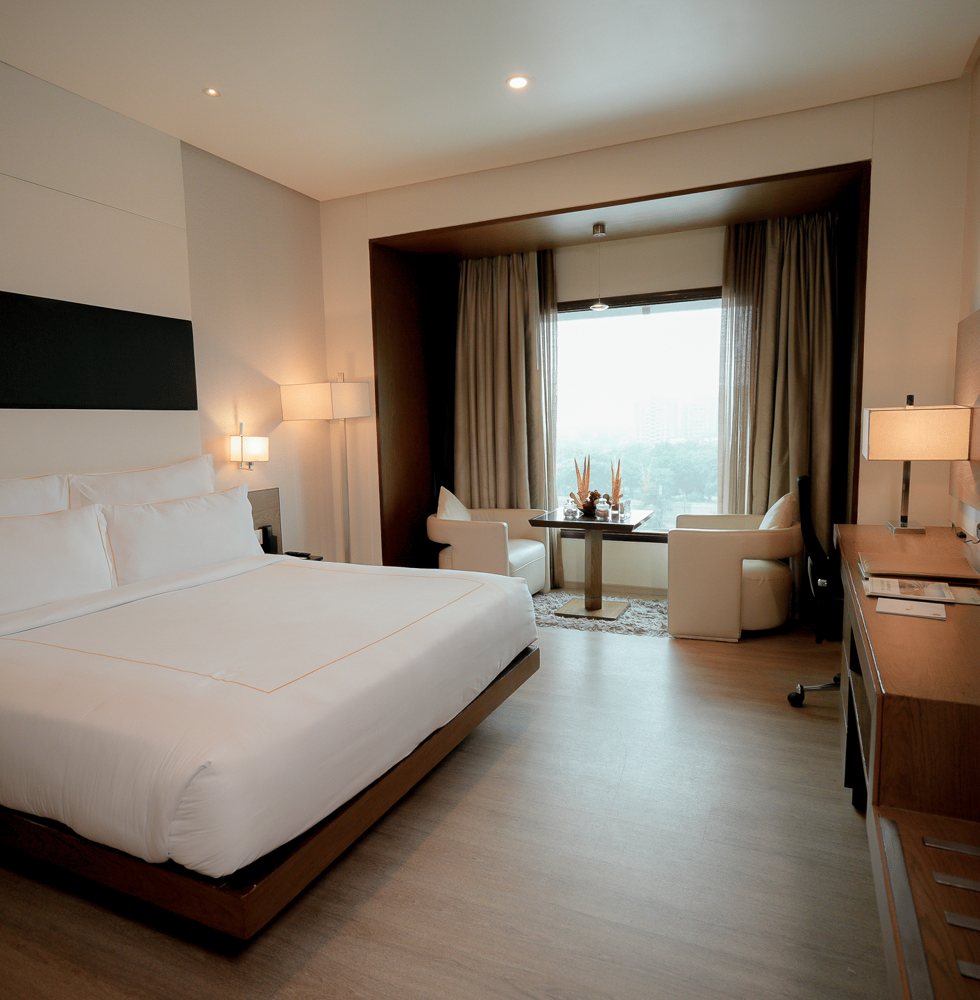 Deluxe room with king size bed and warm lighting at Narayani Heights Hotel & Resorts, Ahmedabad.